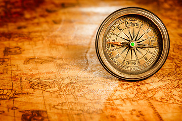 Image showing Vintage compass lies on an ancient world map.