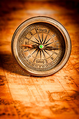 Image showing Vintage compass lies on an ancient world map.