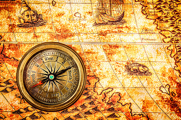 Image showing Vintage compass lies on an ancient world map.