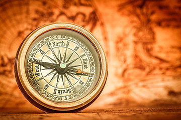 Image showing Vintage compass lies on an ancient world map.