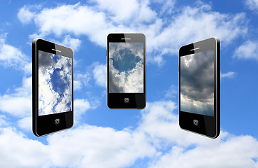 Image showing three modern mobile phones on the cloudy sky