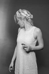 Image showing Blonde girl in mini dress and stylish hairstyle with biscuit in hand looks back over her shoulder