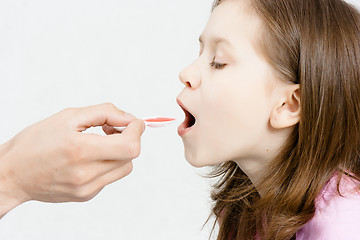 Image showing Treatment of the child. Girl is drinking medicinal syrup