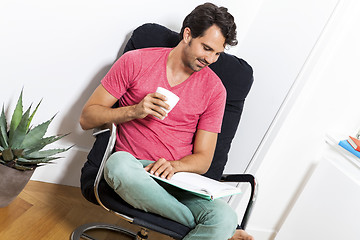 Image showing Man Sitting on Chair with Book and a Drink