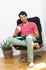 Image showing Man Sitting on Chair with Book and a Drink