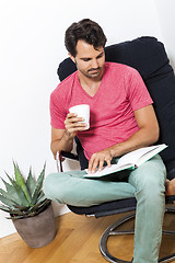 Image showing Man Sitting on Chair with Book and a Drink