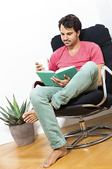 Image showing Man Sitting on Chair with Book and a Drink