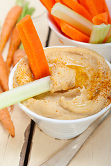 Image showing fresh hummus dip with raw carrot and celery 