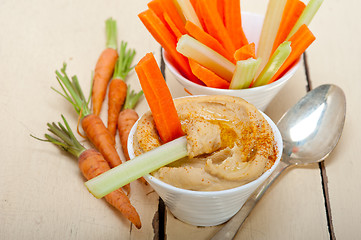 Image showing fresh hummus dip with raw carrot and celery 