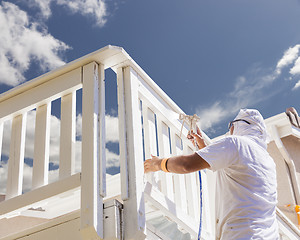 Image showing House Painter Spray Painting A Deck of A Home