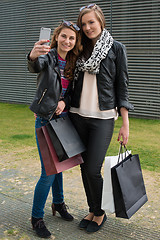 Image showing Two attractive girls making a selfie after shopping