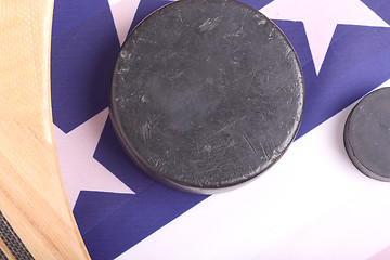 Image showing Hockey equipment including a stick and puck on an American flag to infer a patriotic American sport.