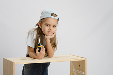 Image showing Girl-collector of furniture with a screwdriver wearily leaned on the cabinet