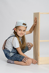 Image showing Little girl in overalls collector of furniture turn screw on dresser