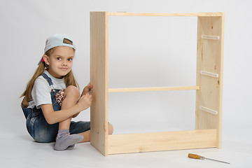 Image showing Girl collects garbage furniture chest of drawers