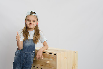 Image showing Girl in overalls collector relies on the chest shows class