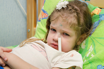 Image showing Little girl lying in bed with a thermometer