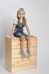 Image showing Girl in overalls collector relies on the chest shows class