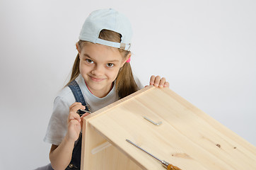 Image showing Little girl in image collector of furniture turn screw
