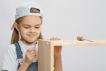 Image showing Girl clothing collector furniture trying to screw