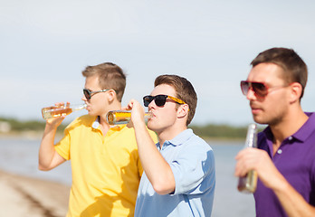 Image showing happy friends with beer bottles on beach