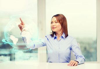 Image showing smiling woman pointing to earth hologram