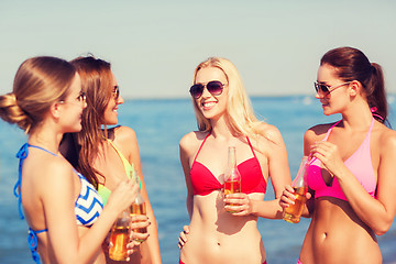 Image showing group of smiling young women drinking on beach