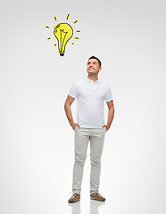 Image showing smiling man looking up to lighting bulb
