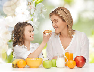 Image showing happy mother and daughter eating breakfast