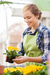 Image showing happy woman holding flowers in greenhouse