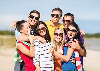 Image showing group of happy friends hugging on beach