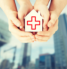 Image showing hands holding paper house with red cross