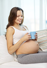 Image showing happy pregnant woman with cup drinking tea at home