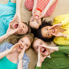 Image showing smiling people lying down on floor and screaming