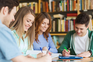 Image showing happy students writing to notebooks in library