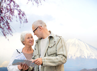 Image showing happy senior couple with travel map over mountains