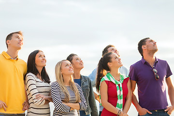 Image showing group of happy friends looking up on beach