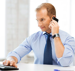 Image showing smiling businessman with smartphone in office