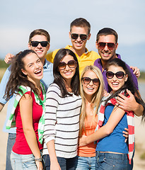 Image showing group of happy friends hugging on beach