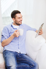 Image showing smiling man with tablet pc and cup at home