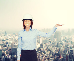 Image showing businesswoman in helmet holding something on palm