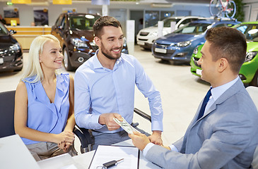 Image showing happy couple with car dealer in auto show or salon