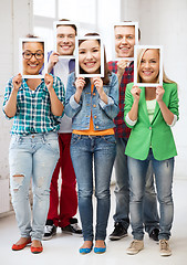 Image showing happy friends covering faces with own photos