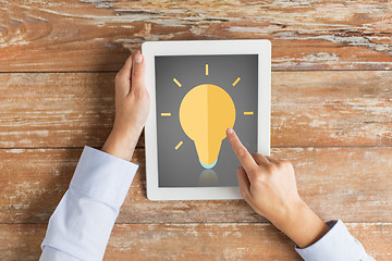 Image showing close up of hands with lighting bulb on tablet pc