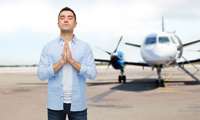 Image showing man praying over airplane on runway background