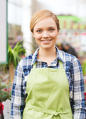 Image showing happy woman with flowers in greenhouse