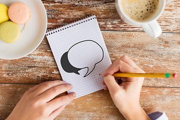 Image showing close up of hands drawing text bubble in notebook