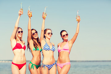 Image showing group of smiling young women drinking on beach