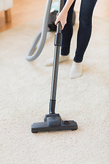 Image showing close up of woman legs with vacuum cleaner at home