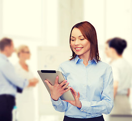 Image showing smiling woman looking at tablet pc at office